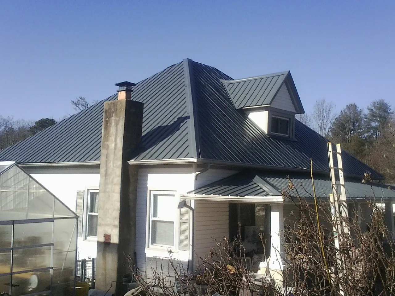 Dark blue standing seam metal roof on a white farmhouse with dormer — Slate & Tile Roof Repair by Roofing Brothers in Greenland