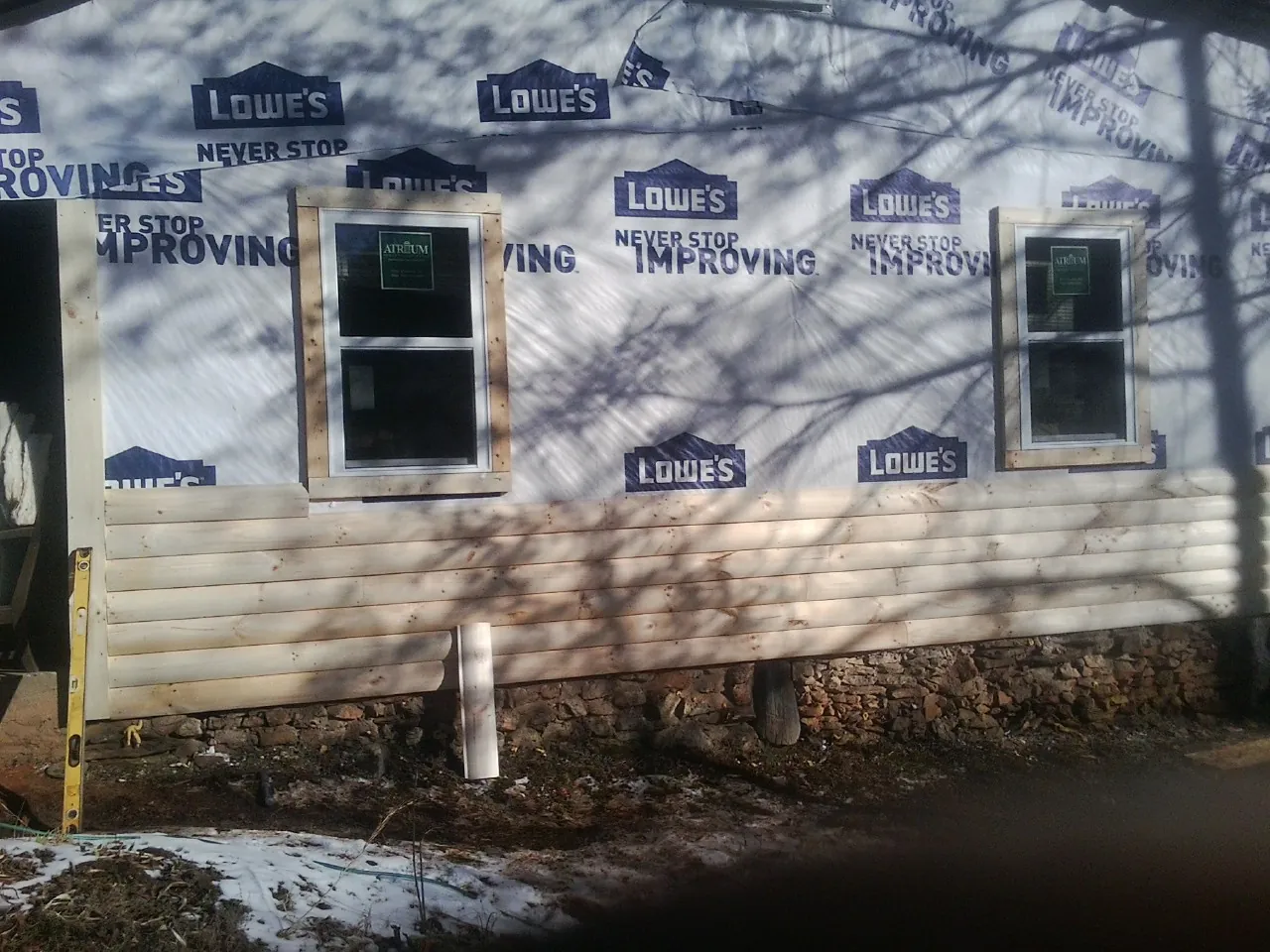 House wrap and new log siding going up on an exterior wall in Greenland