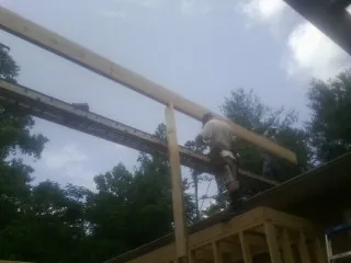 Carpenter setting a ridge beam over a new addition frame — Ice Dam Removal by Roofing Brothers in Greenland