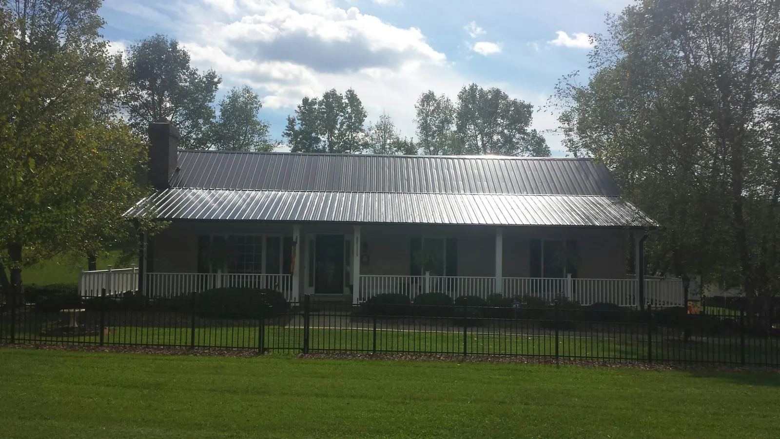 Gray metal roof on a brick ranch with a full width front porch — Gutter Guard Installation work by our crew in Greenland