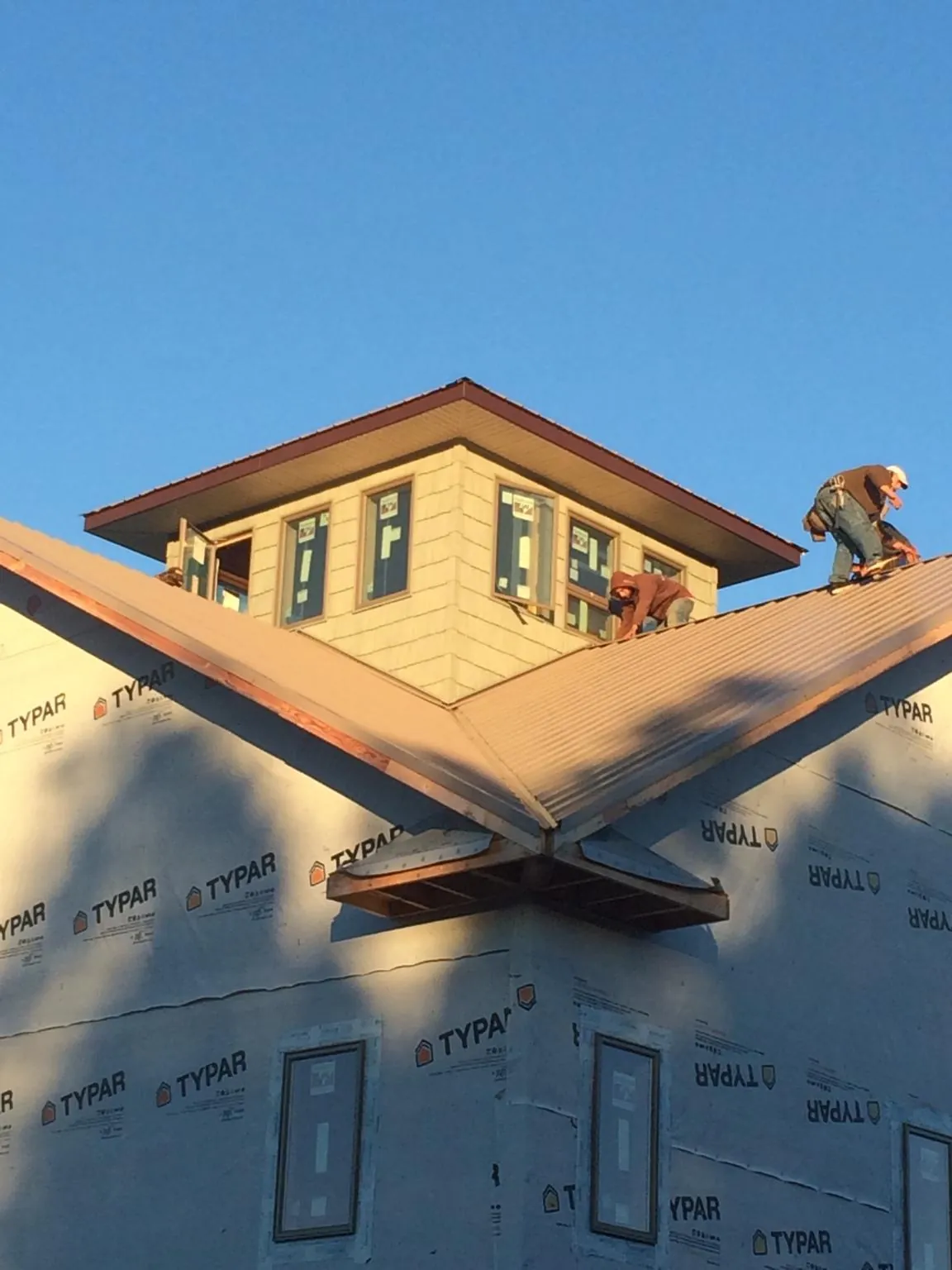 Roofers working around a rooftop cupola on a new metal roof at sunset — Roof Waterproofing in Greenland by Roofing Brothers